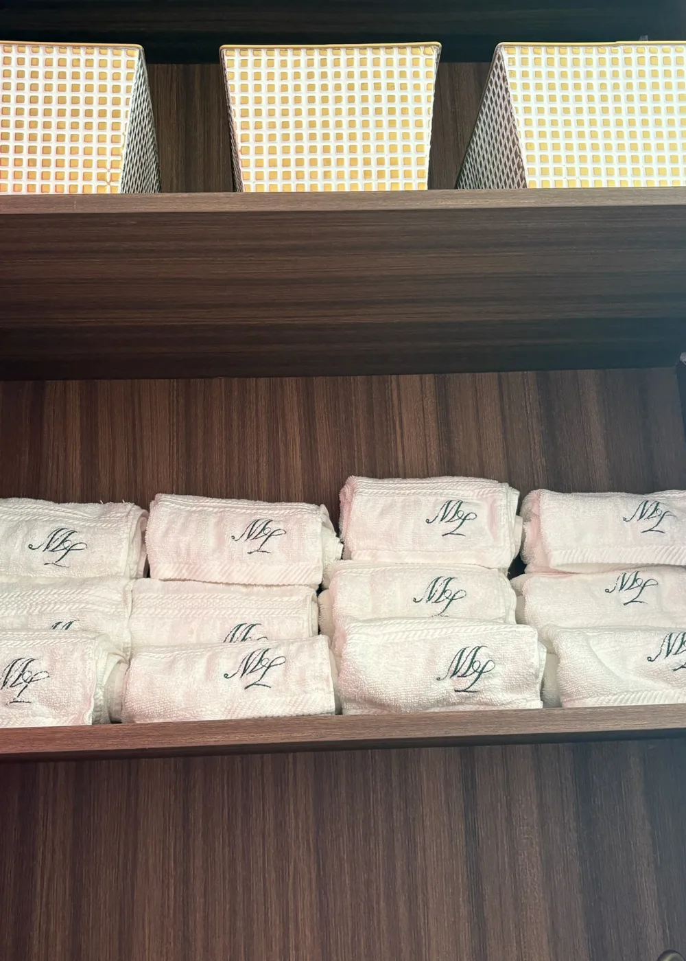 Rolled Maison Lagree monogrammed towels on the changing-room shelf